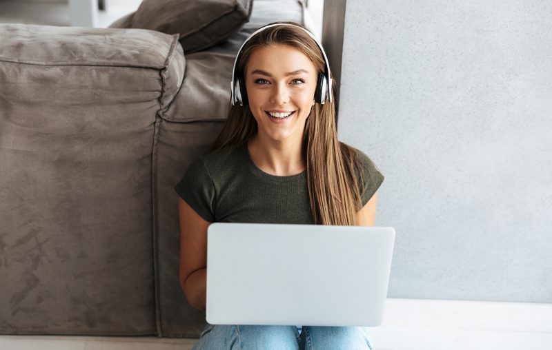 tjej framför en laptop sittande på golvet